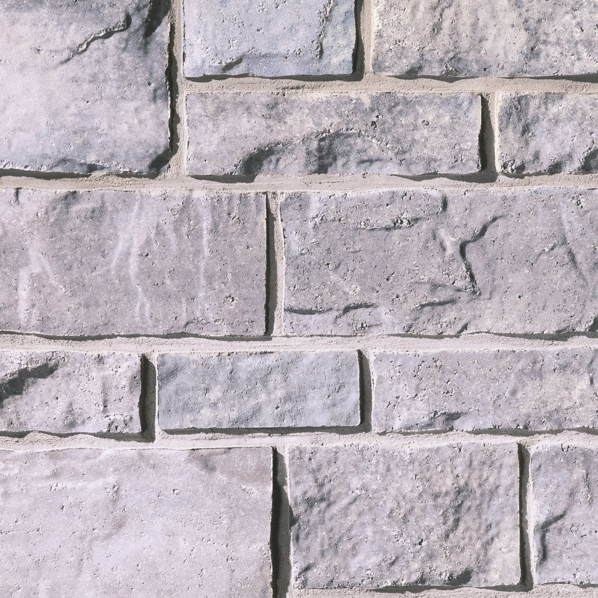 Mur en pierre grise avec des blocs de différentes tailles et textures, créant un motif naturel et robuste.