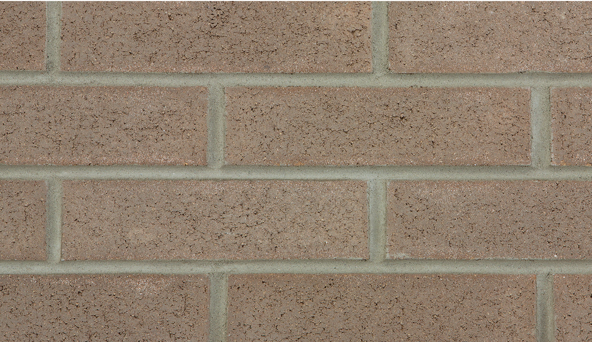 Mur en briques de couleur beige avec des joints gris, texture rugueuse.