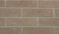 Mur en briques de couleur beige, avec des joints gris, montrant une texture rugueuse et uniforme.