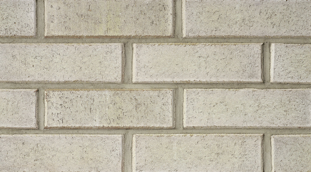 Mur de briques en argile de couleur beige, avec des joints visibles entre les briques. Texture rugueuse et uniforme.