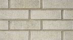 Mur de briques en argile de couleur beige, avec des joints visibles entre les briques. Texture rugueuse et uniforme.