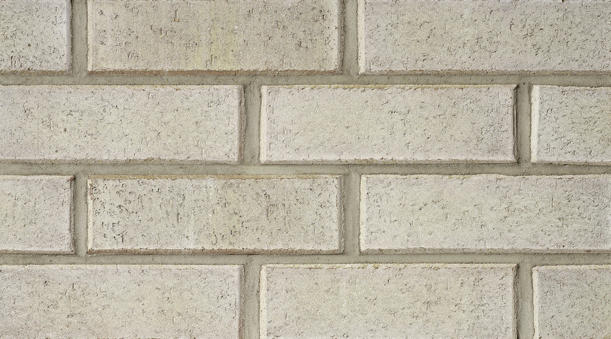 Mur de briques en argile de couleur beige, avec des joints visibles entre les briques. Texture rugueuse et uniforme.