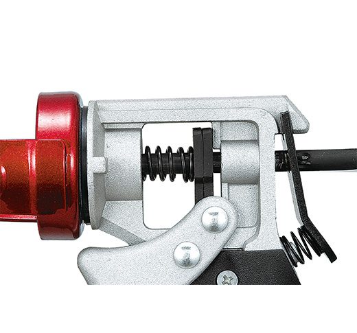 Pistolet à calfeutrer rouge et argent, conçu pour appliquer des matériaux durs, avec une poignée rotative.