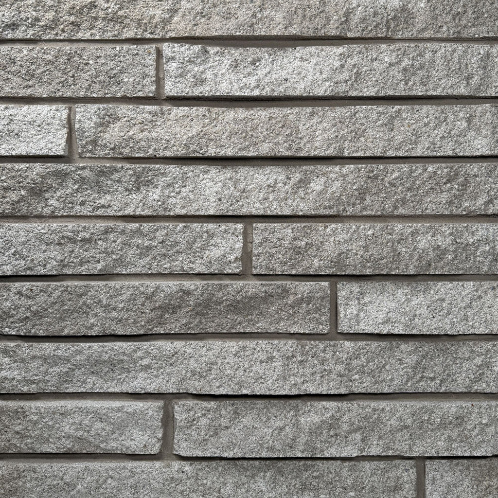 Mur en pierre grise avec des blocs rectangulaires disposés horizontalement, créant une texture rugueuse et moderne.