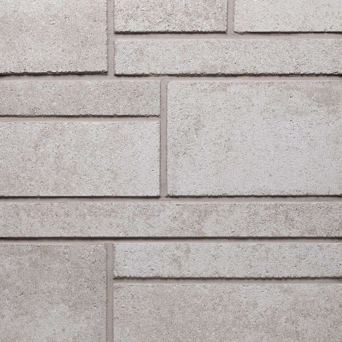 Mur en béton texturé de couleur beige clair avec des motifs de briques rectangulaires.
