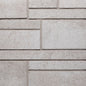 Mur en béton texturé de couleur beige clair avec des motifs de briques rectangulaires.