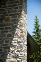 Pierre naturelle grise avec des nuances de brun, utilisée pour le revêtement extérieur et intérieur.