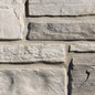 Mur en pierre grise avec des textures variées, présentant des blocs de pierre de différentes tailles et finitions.