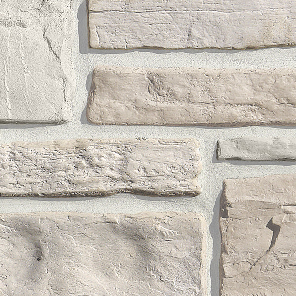 Pierre décorative en différentes teintes de gris et beige, avec une texture rugueuse et des bords irréguliers, disposée en motifs.