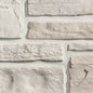 Pierre décorative en différentes teintes de gris et beige, avec une texture rugueuse et des bords irréguliers, disposée en motifs.