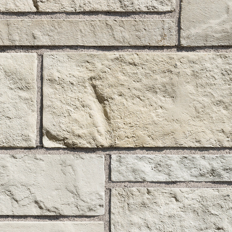 Mur en pierre de couleur beige clair, avec des blocs de différentes tailles et textures, créant un motif naturel.