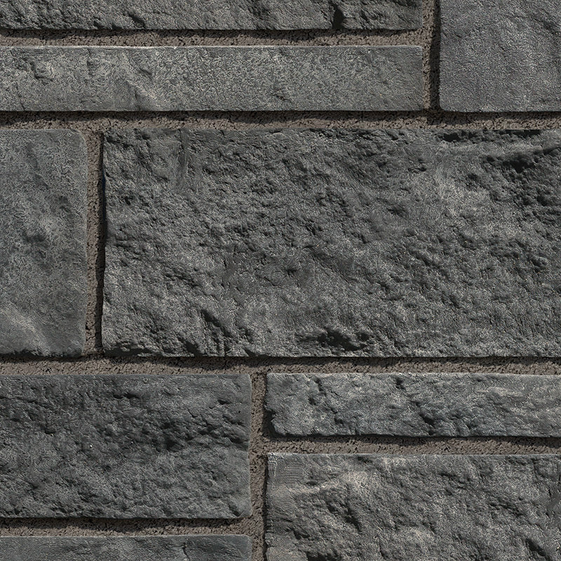 Mur en pierre grise texturée avec des blocs de différentes tailles, offrant un aspect robuste et moderne.