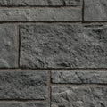 Mur en pierre grise texturée avec des blocs de différentes tailles, offrant un aspect robuste et moderne.