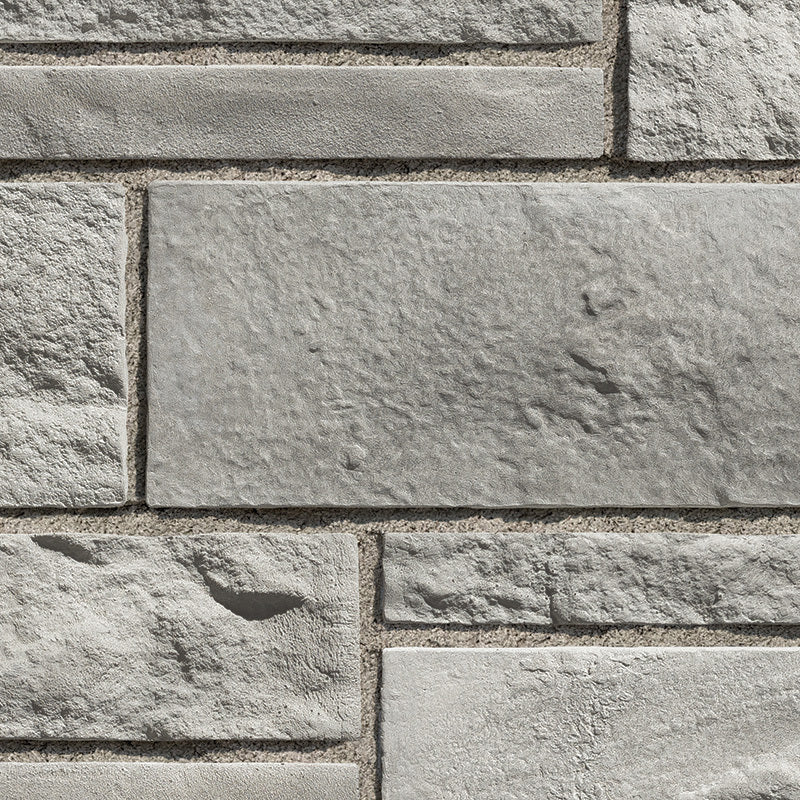 Mur en pierre grise avec des blocs de différentes tailles et textures, créant un motif de maçonnerie.