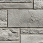 Mur en pierre grise avec des blocs de différentes tailles et textures, créant un motif de maçonnerie.