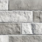Briques en pierre grise et blanche, avec une texture rugueuse, disposées en motif de maçonnerie.