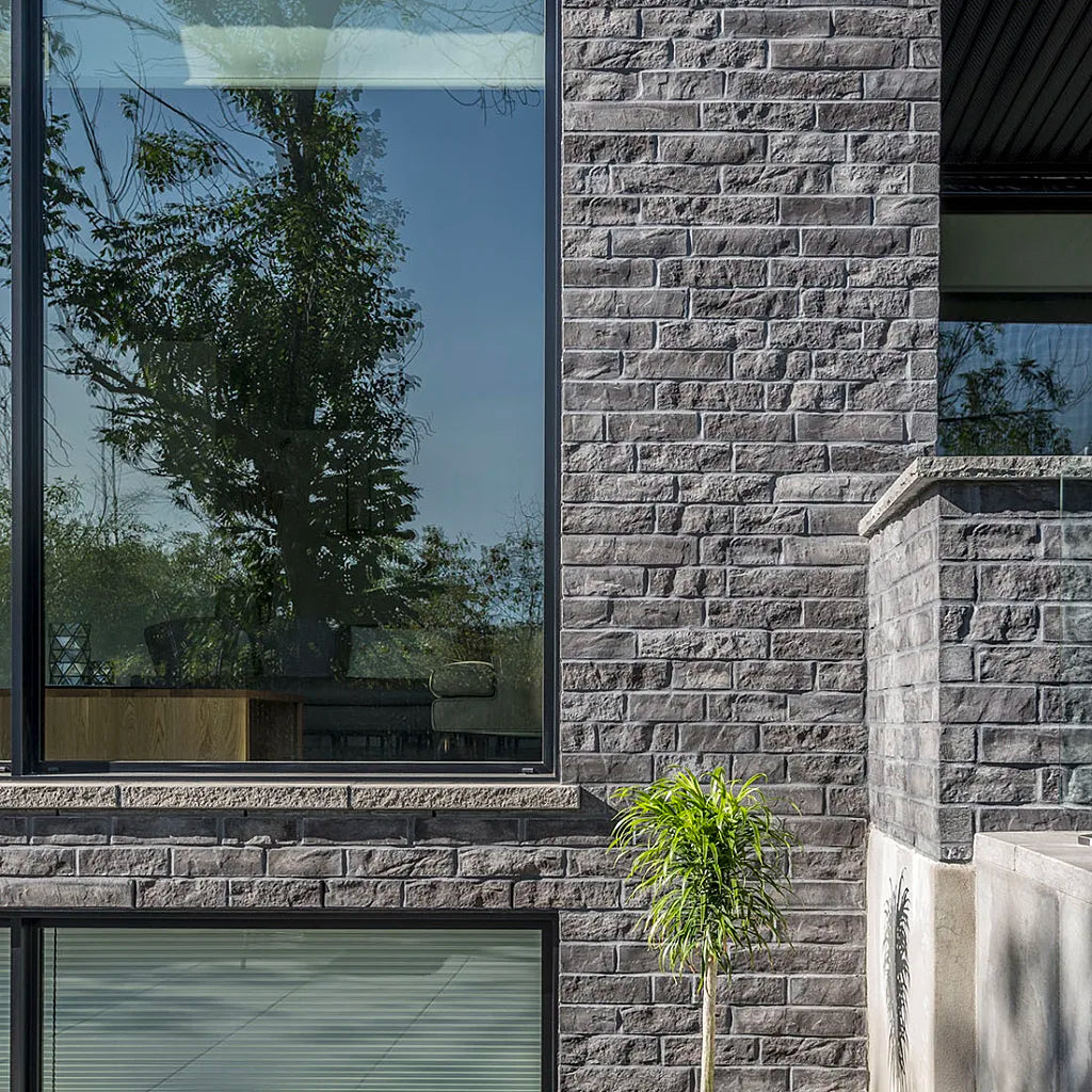 Mur en briques grises avec texture rugueuse, disposées en motif de maçonnerie.