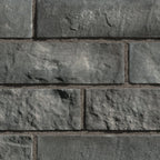 Briques en pierre grise avec texture rugueuse, disposées en rangées sur un mur.
