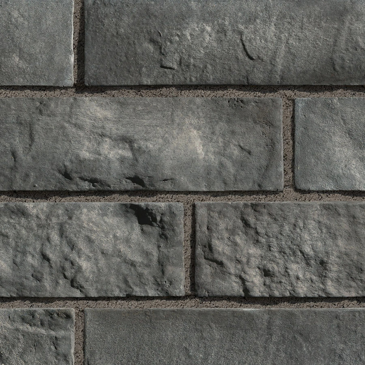 Briques en pierre grise avec texture rugueuse, disposées en rangées sur un mur.
