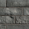 Briques en pierre grise avec texture rugueuse, disposées en motif de maçonnerie.