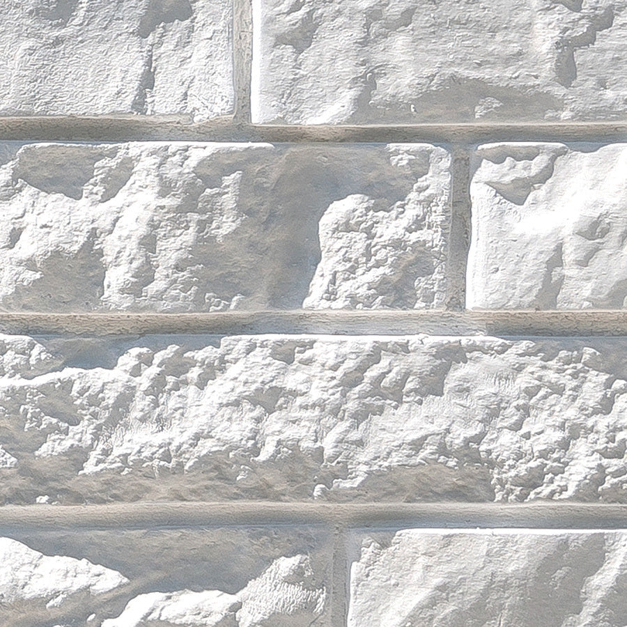 Mur en briques grises texturées avec des joints visibles, créant un effet de maçonnerie.