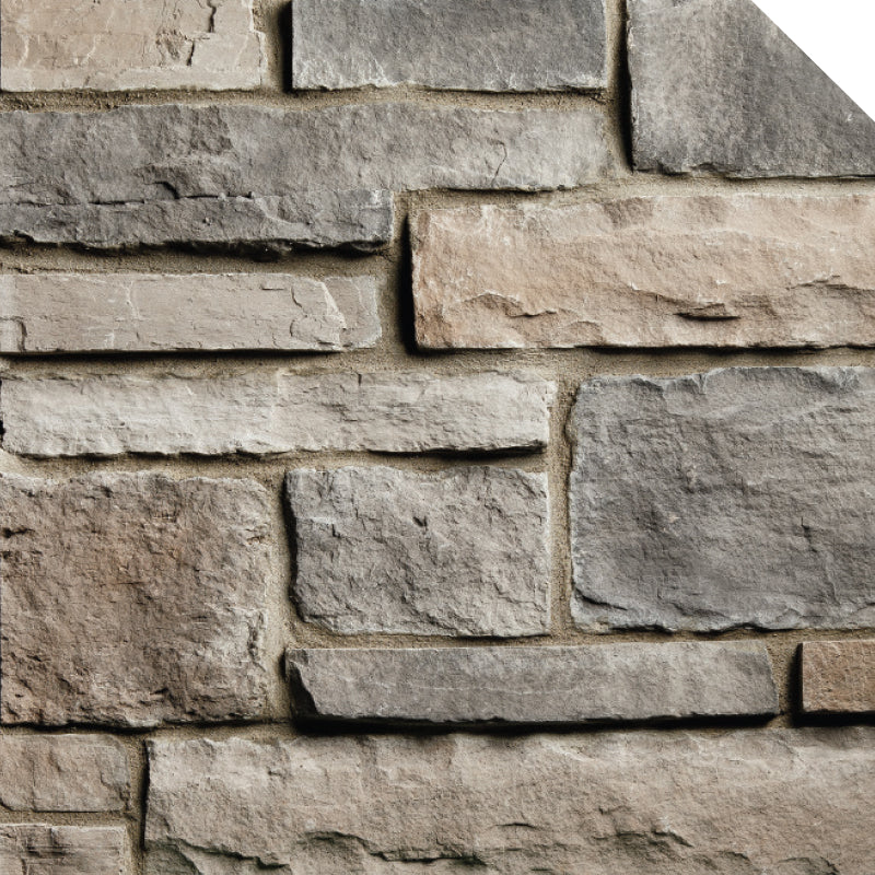 Pierre décorative en différentes teintes de gris et beige, disposée en motifs de maçonnerie sur un mur.