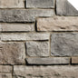 Pierre décorative en différentes teintes de gris et beige, disposée en motifs de maçonnerie sur un mur.