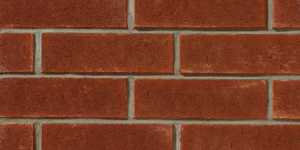 Mur de briques rouges avec joints en ciment, texture rugueuse et uniforme, disposées en motif rectangulaire.