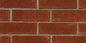Mur de briques rouges avec joints en ciment, texture rugueuse et uniforme, disposées en motif rectangulaire.