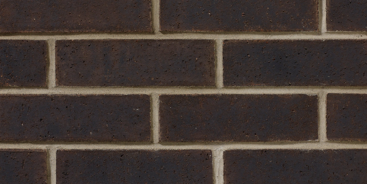 Briques en terre cuite de couleur brun foncé, disposées en motif de maçonnerie sur un mur.