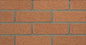 Mur en briques rouges avec des joints en ciment gris, texture rugueuse et uniforme.
