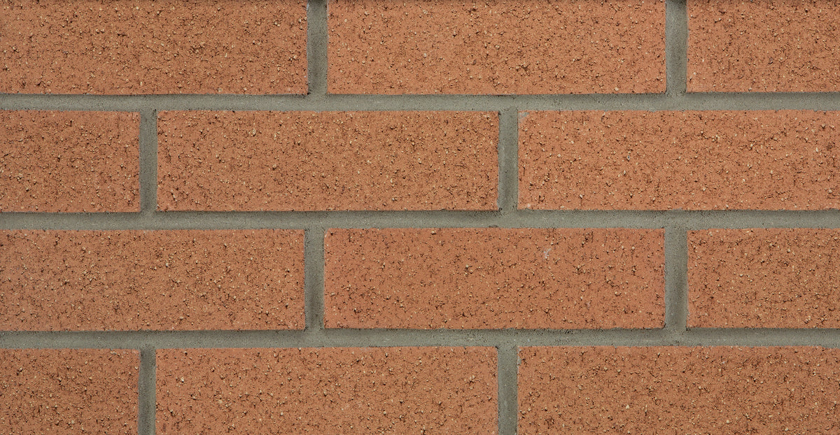 Mur en briques de couleur rougeâtre avec des joints en ciment gris. Texture rugueuse et uniforme.