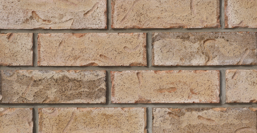 Briques en terre cuite de couleur beige avec des textures variées, disposées en rangées sur un mur.