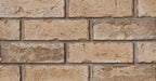 Briques en terre cuite de couleur beige avec des textures variées, disposées en rangées sur un mur.