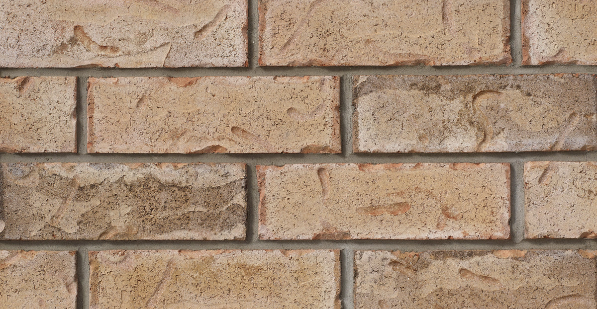 Briques en terre cuite de couleur beige avec des textures variées, disposées en motif de maçonnerie.