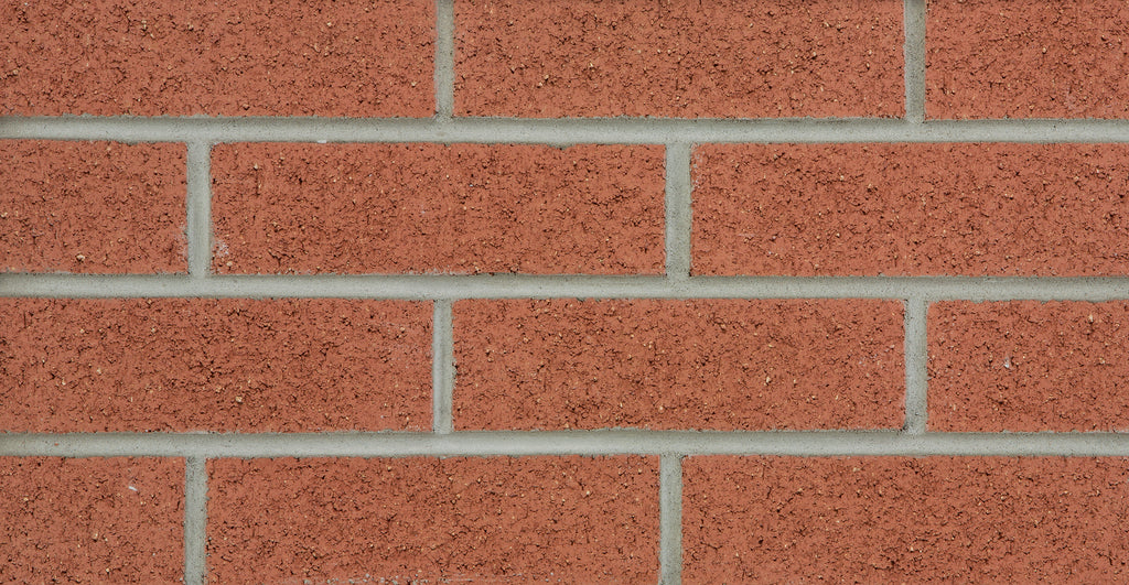 Mur de briques rouges avec des joints de mortier gris, texture rugueuse et uniforme.