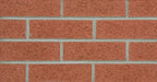 Mur de briques rouges avec des joints de mortier gris, texture rugueuse et uniforme.