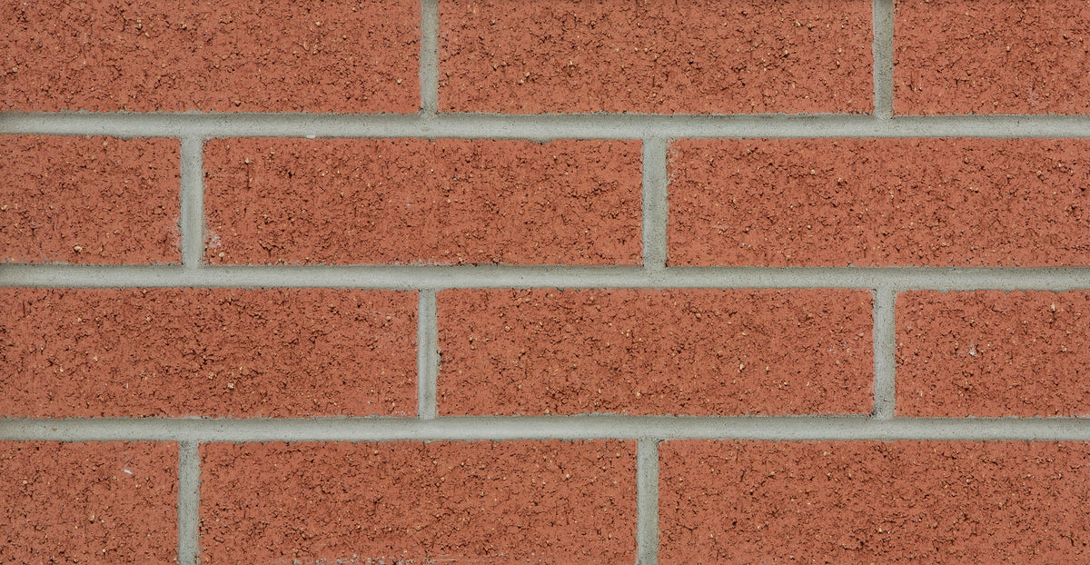 Mur de briques rouges avec des joints de mortier gris, texture rugueuse et uniforme.
