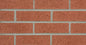 Mur en briques rouges avec joints gris, texture rugueuse et motif de maçonnerie.