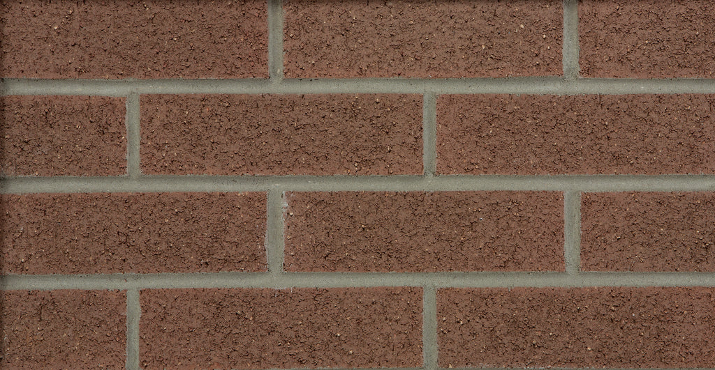 Mur en briques rouges avec des joints gris, présentant une texture uniforme et des lignes droites.