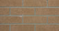 Mur en briques de couleur brun clair avec des joints gris, texture rugueuse et uniforme.