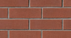 Mur de briques rouges avec joints gris, texture rugueuse et uniforme, disposées en rangées.