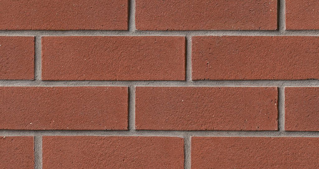 Mur de briques rouges avec joints gris, texture rugueuse et uniforme, disposées en rangées.