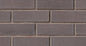 Mur de briques en couleur brun foncé, avec des joints de mortier visibles entre les briques. Texture rugueuse et uniforme.