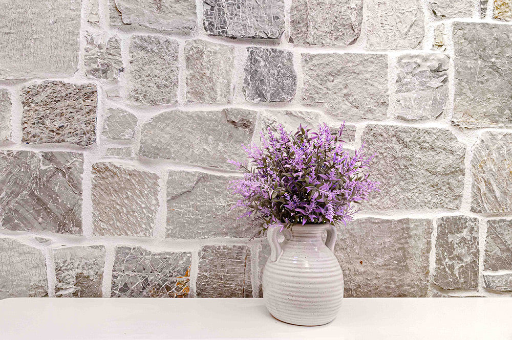 Mur en pierre naturelle grise avec des nuances de beige et blanc cassé.