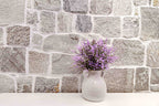 Mur en pierre naturelle grise avec des nuances de beige et blanc cassé.