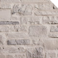 Mur en pierre naturelle de couleur claire, avec des textures variées et des formes irrégulières, créant un aspect rustique.