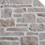 Mur en pierre grise avec des blocs de différentes tailles et textures, créant un motif de maçonnerie.