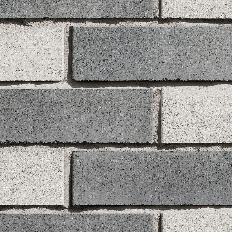 Briques en béton de couleur grise et blanche, disposées en motif alterné sur un mur.