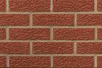 Mur de briques rouges texturées avec des joints en ciment beige, disposées en motif de maçonnerie.